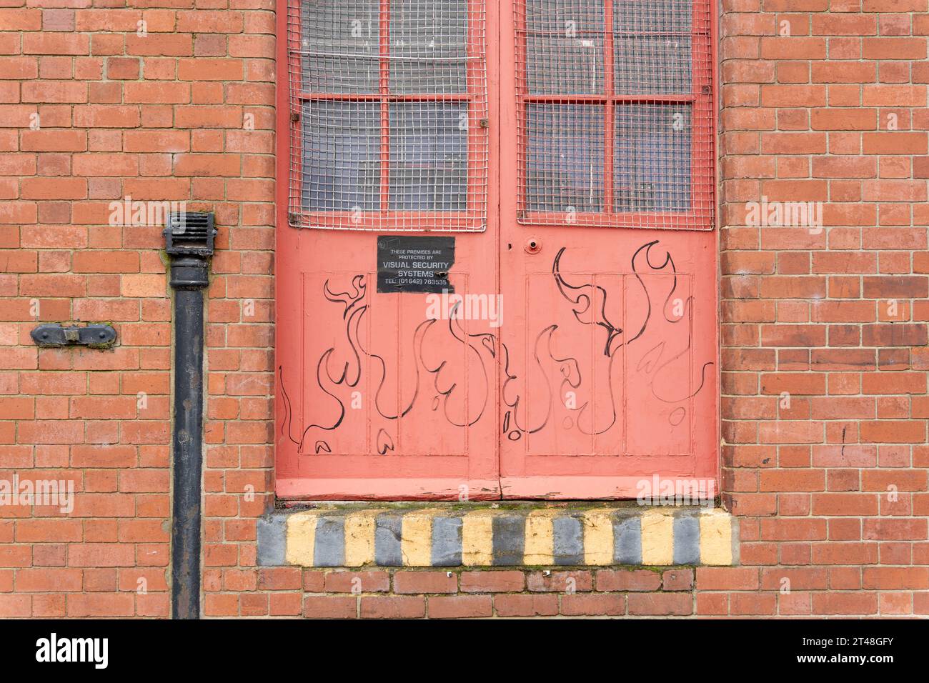 Flammen gezeichnet auf einem roten Eingang in School Croft, hinter Exchange Place, Exchange Square, Middlesbrough, Großbritannien Stockfoto