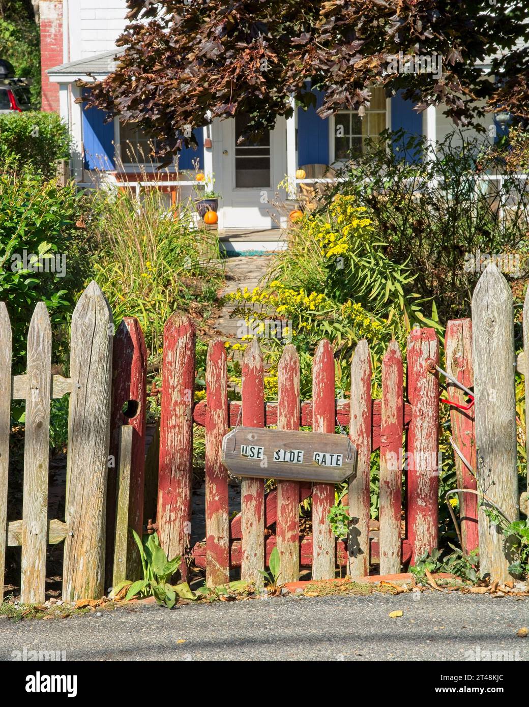 Verwittertes rotes Pfostentor mit Schild „Use Side Gate“ schützt den Vordereingang zum traditionellen New England Haus in Provincetown Massachusetts – Oktober 2023 Stockfoto