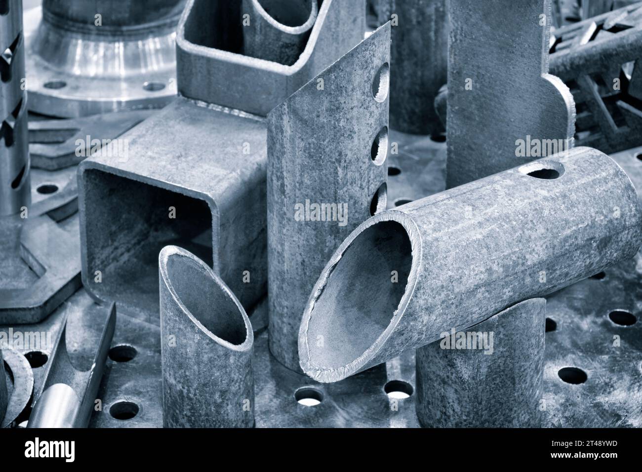 Verschiedene schwarze Metallteile geschnitten, gebohrt, Rohre, quadratischer Abschnitt als Hintergrund des Industriekonzepts Stockfoto