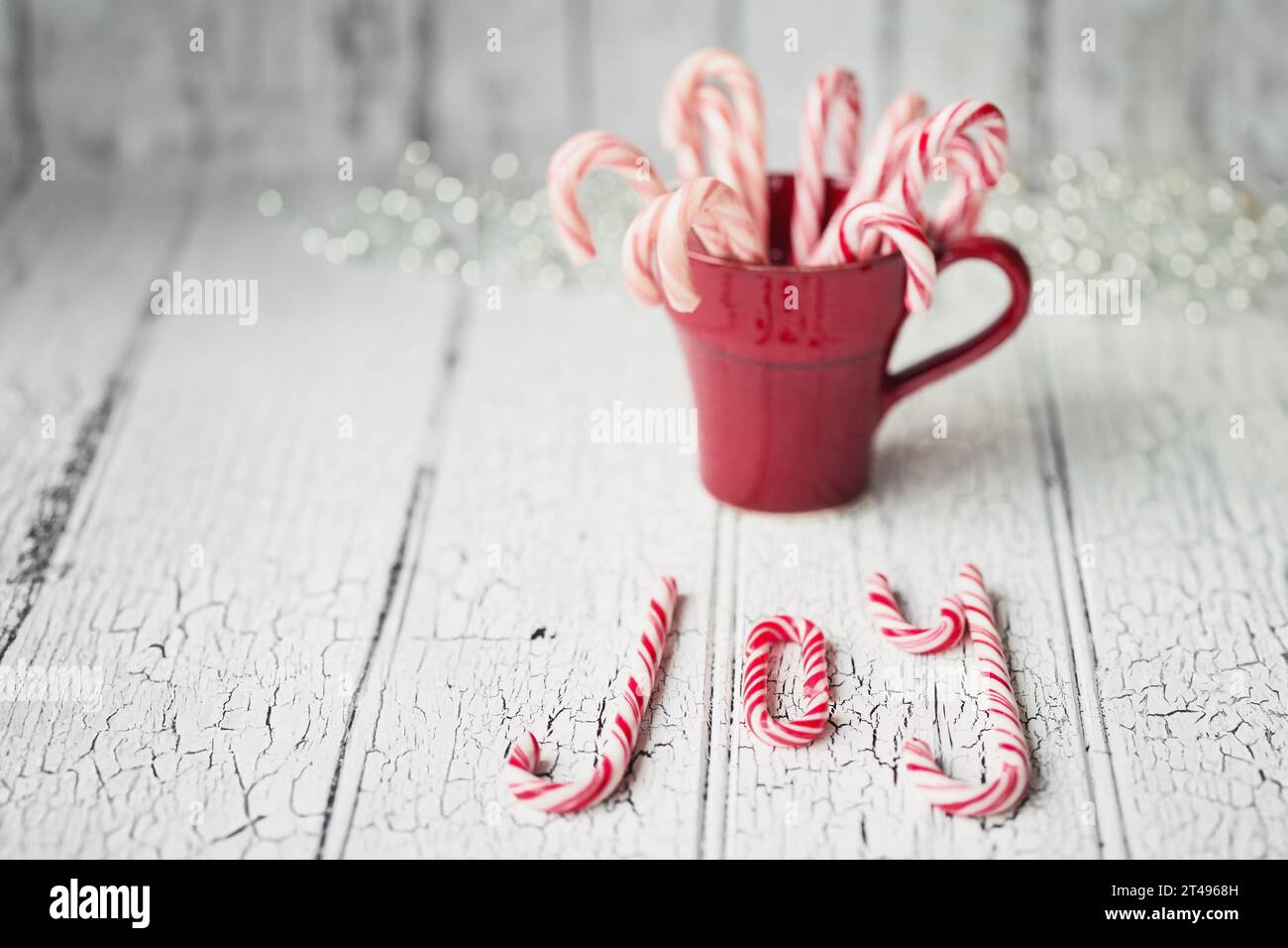 Rote Tasse gefüllt mit Zuckerstangen, die Freude auf weißem Hintergrund schreiben Stockfoto