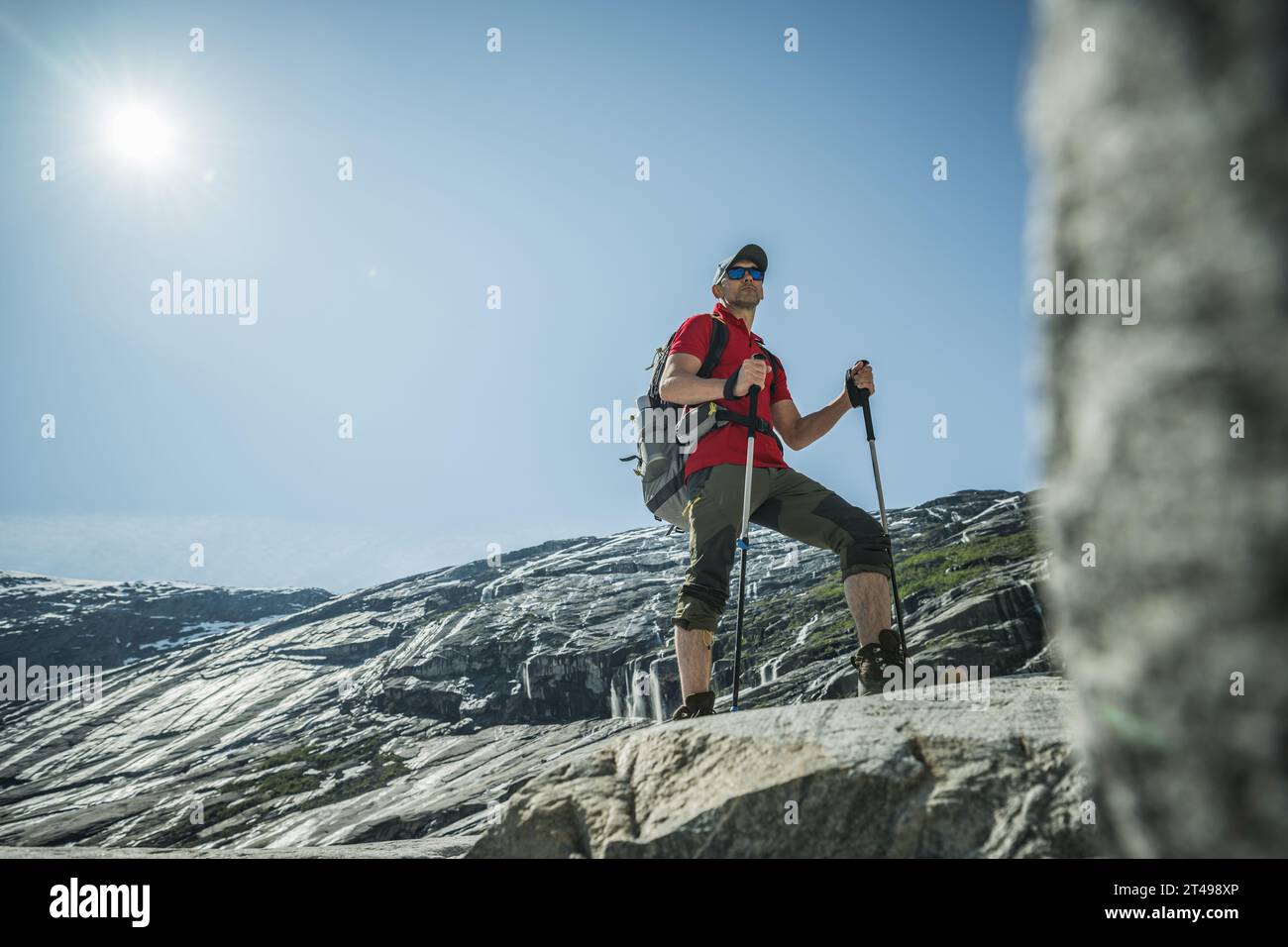 Kaukasischer Tourist mit Wanderstöcken und einem Rucksack in seinen 40ern auf einem norwegischen Sommerweg. Norwegen, Europa. Stockfoto