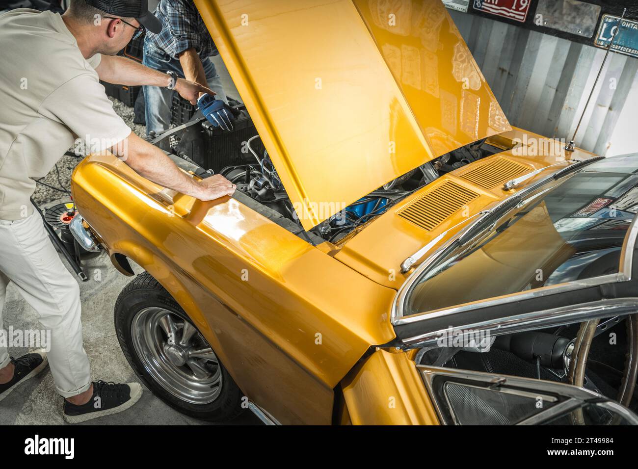 Zwei kaukasische American Classic Cars, die am Motor des Fahrzeugs arbeiten Stockfoto