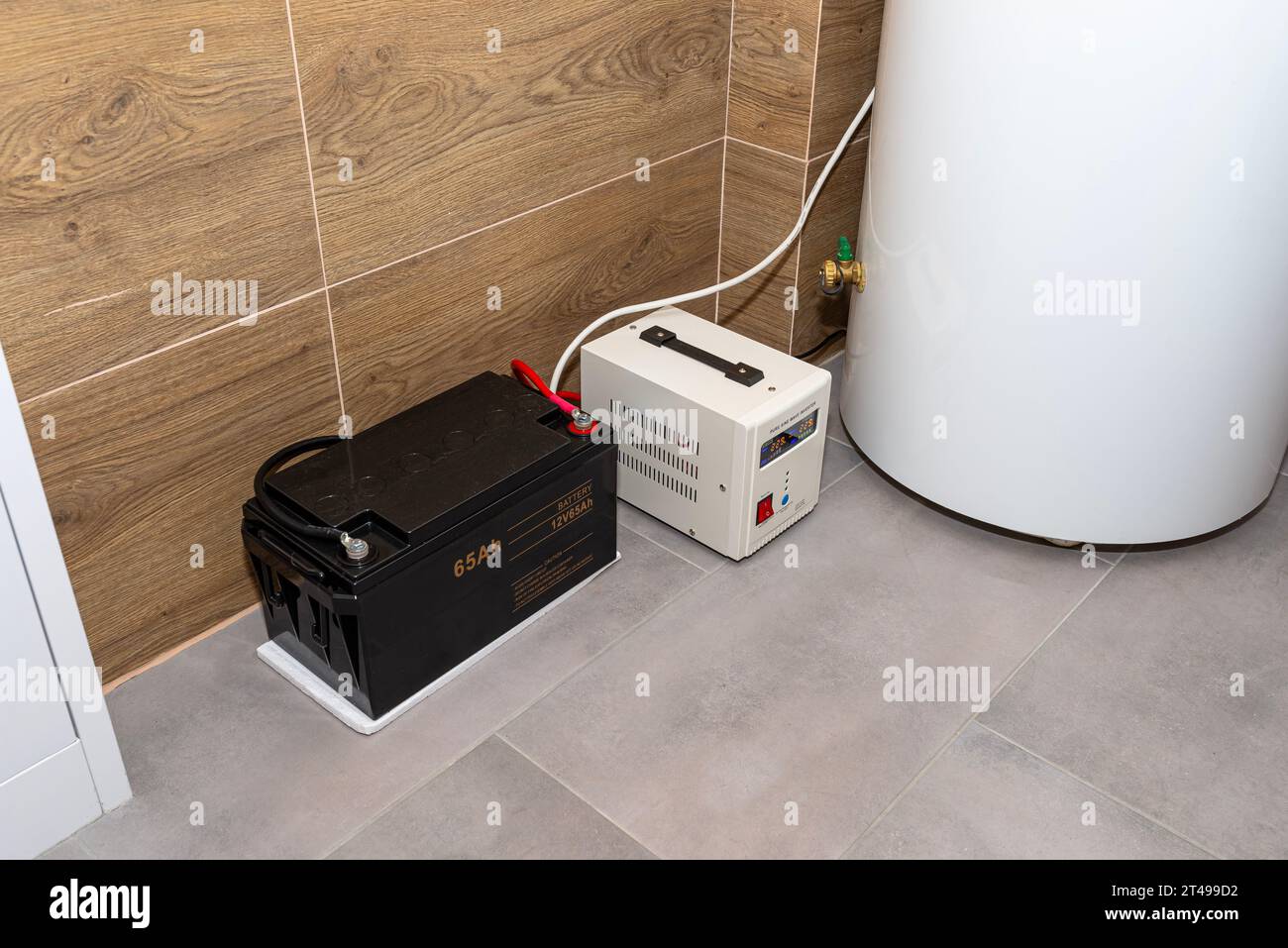 Moderner Gaskesselraum mit Holzkeramikfliesen, sichtbare Notstromversorgung mit 12-Volt-Batterie. Stockfoto