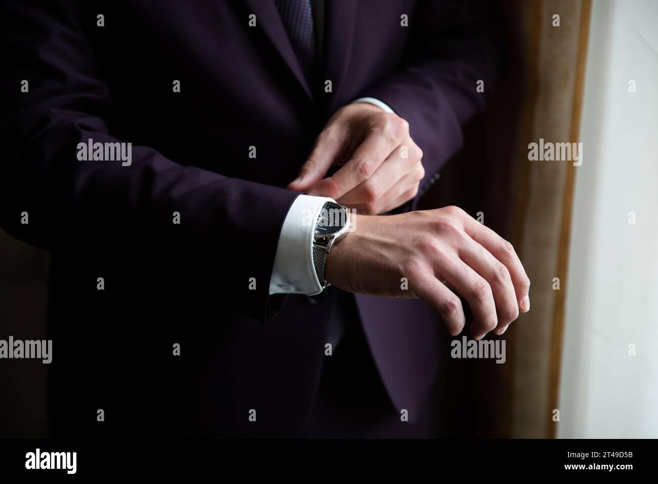 Nahaufnahme eines Mannes, der die Armbanduhr anpasst und den eleganten Anzug und die weiße Manschette hervorhebt. Zeigt Professionalität und Raffinesse. Stockfoto