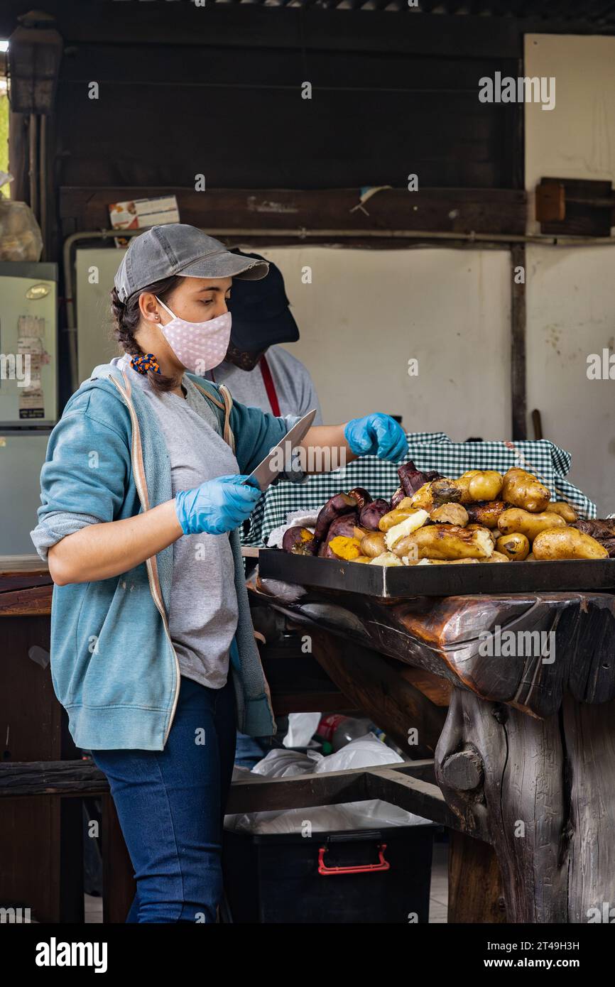 COLONIA SUIZA, SAN CARLOS DE BARILOCHE, ARGENTINIEN - 10. NOVEMBER 2021: Eine Frau legt Gemüse, das unter Tage als Teil des Curanto-Coffee zubereitet wird, zur Seite Stockfoto
