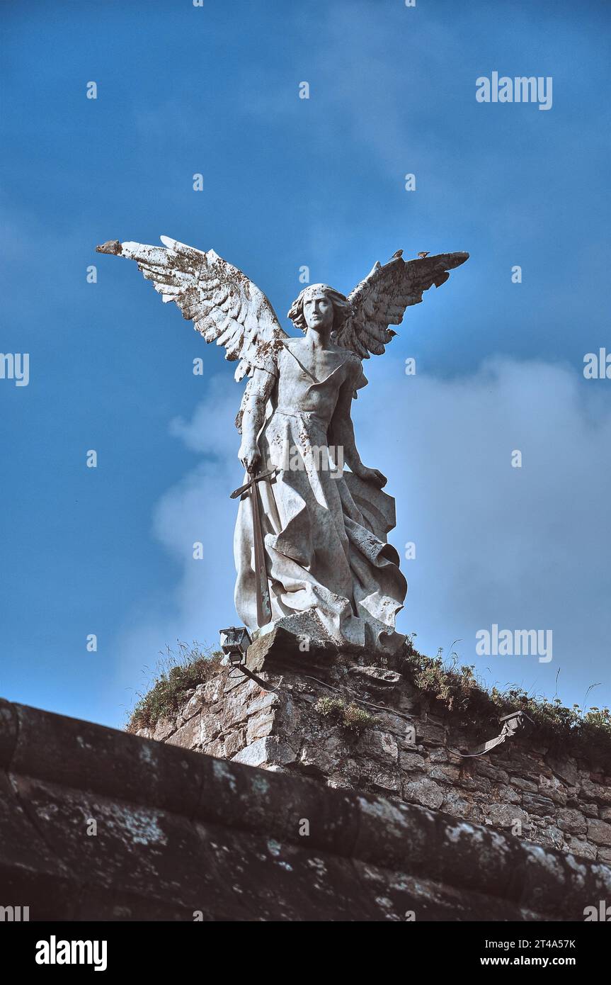 Eine eindrucksvolle Engelsstatue, die auf dem Comillas Cemetery bewacht und sowohl Gelassenheit als auch Wachsamkeit vermittelt Stockfoto