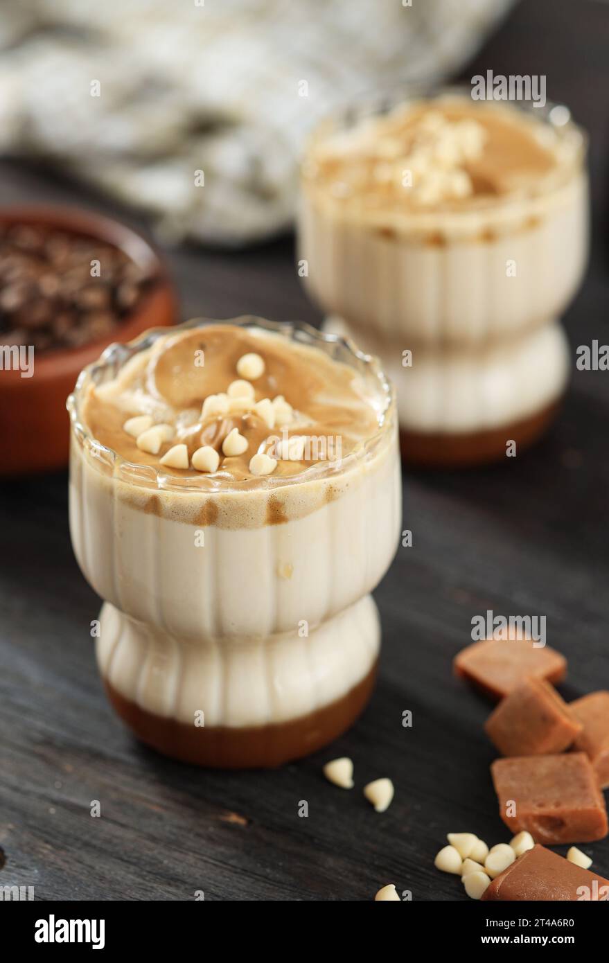 Zwei Gläser Caramel Dalgona Kaffee mit weißer Schokoladenplatte Stockfoto