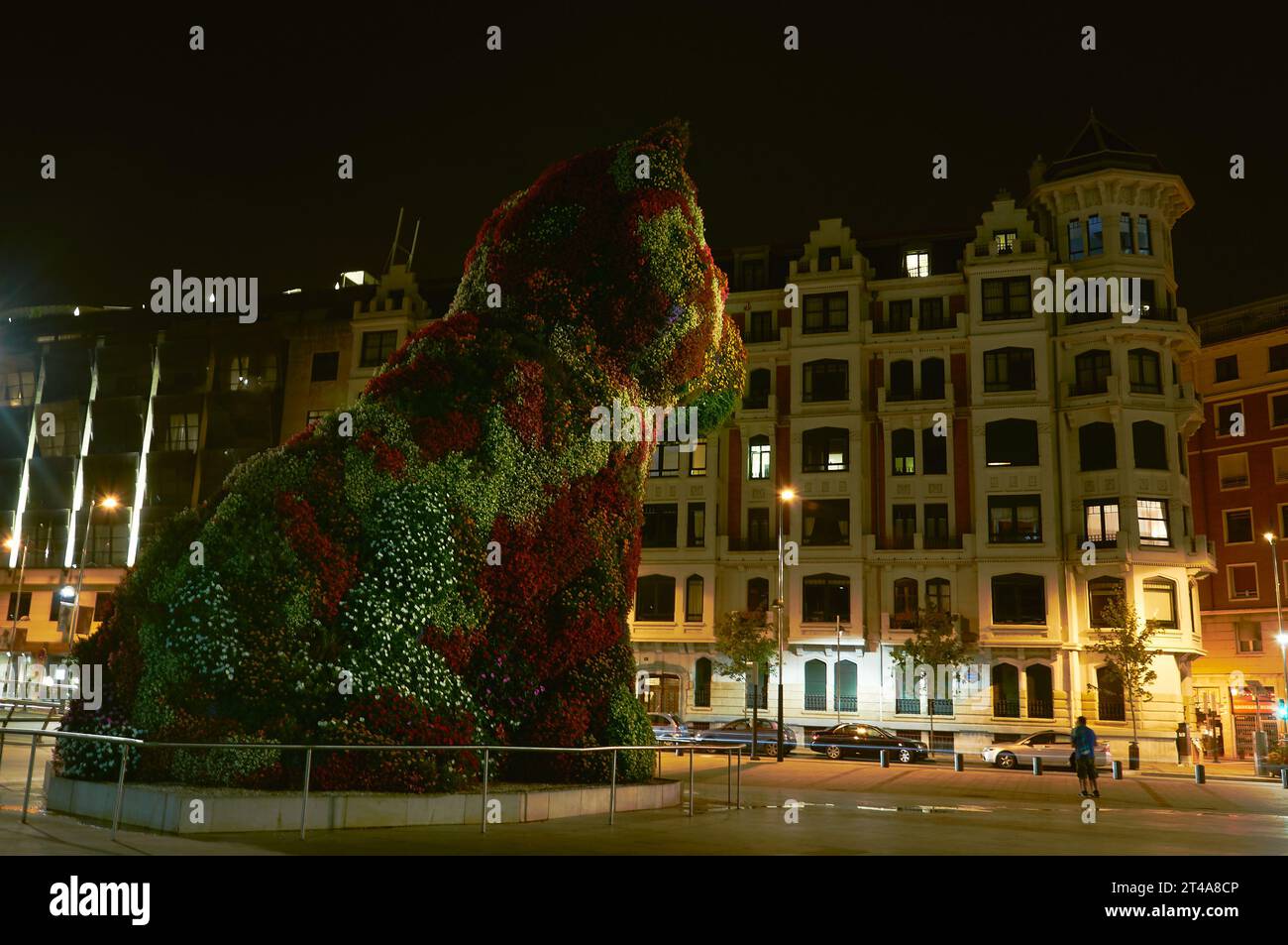Die kultige Hündchenskulptur mit leuchtenden Blumen erweckt Kunst in Bilbao bei Nacht zum Leben Stockfoto