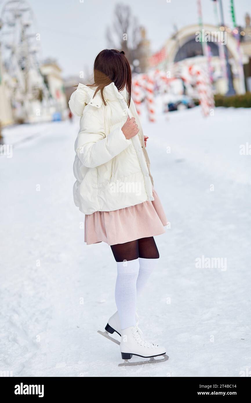 Stilvolle junge Frau Schlittschuhe im Winter im Freien. Festliche Feiertagsstimmung. Träume werden wahr Konzept. Stockfoto