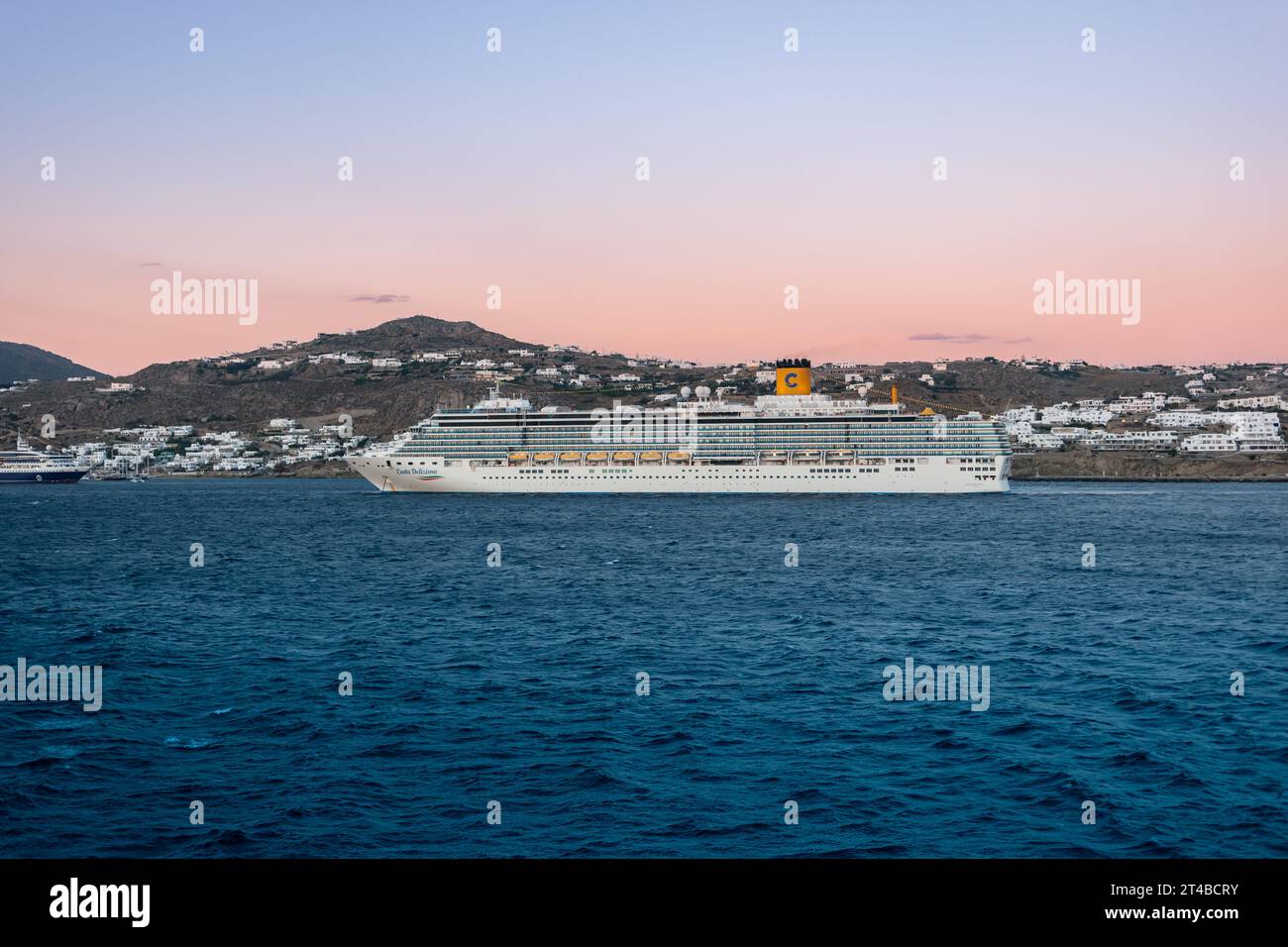 Mykonos, Griechenland - 12. September 2022: Kreuzfahrtschiff Costa Deliziosa von Costa Cruises in der Abenddämmerung im Hafen von Mykonos, Griechenland. Seitenansicht. Stockfoto