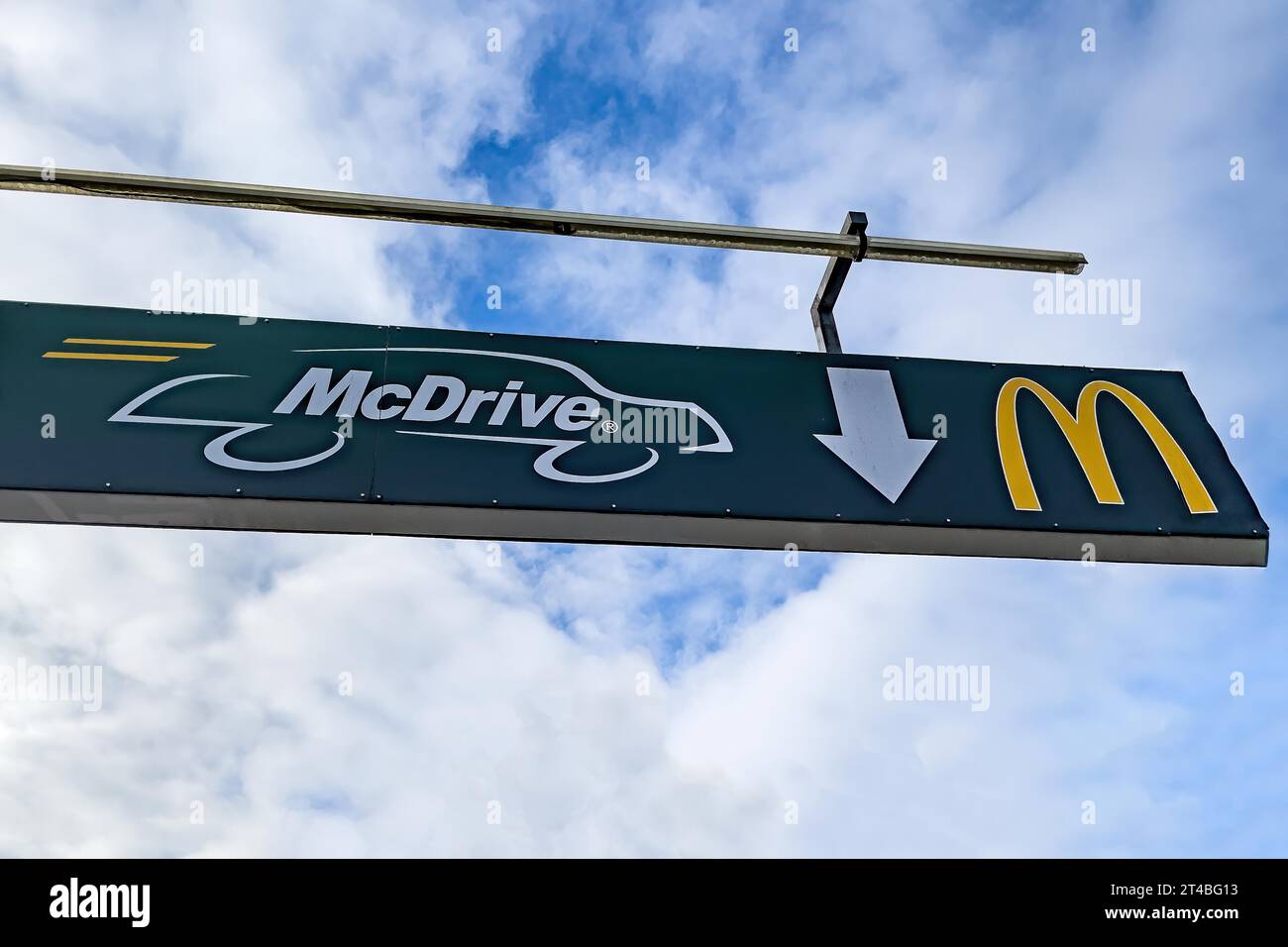 Schild in Höhe am Ständer mit Querstange mit weißer Schrift McDrive und gelbem Logo M von McDonald's über dem Eingang von Drive in zu Fast Food Stockfoto