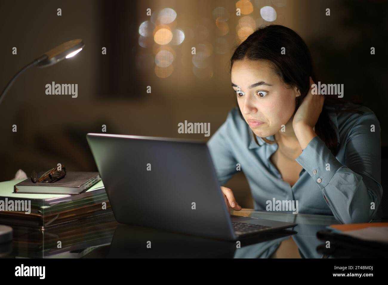 Verwirrter Telearbeiter, der nachts im Homeoffice arbeitet Stockfoto