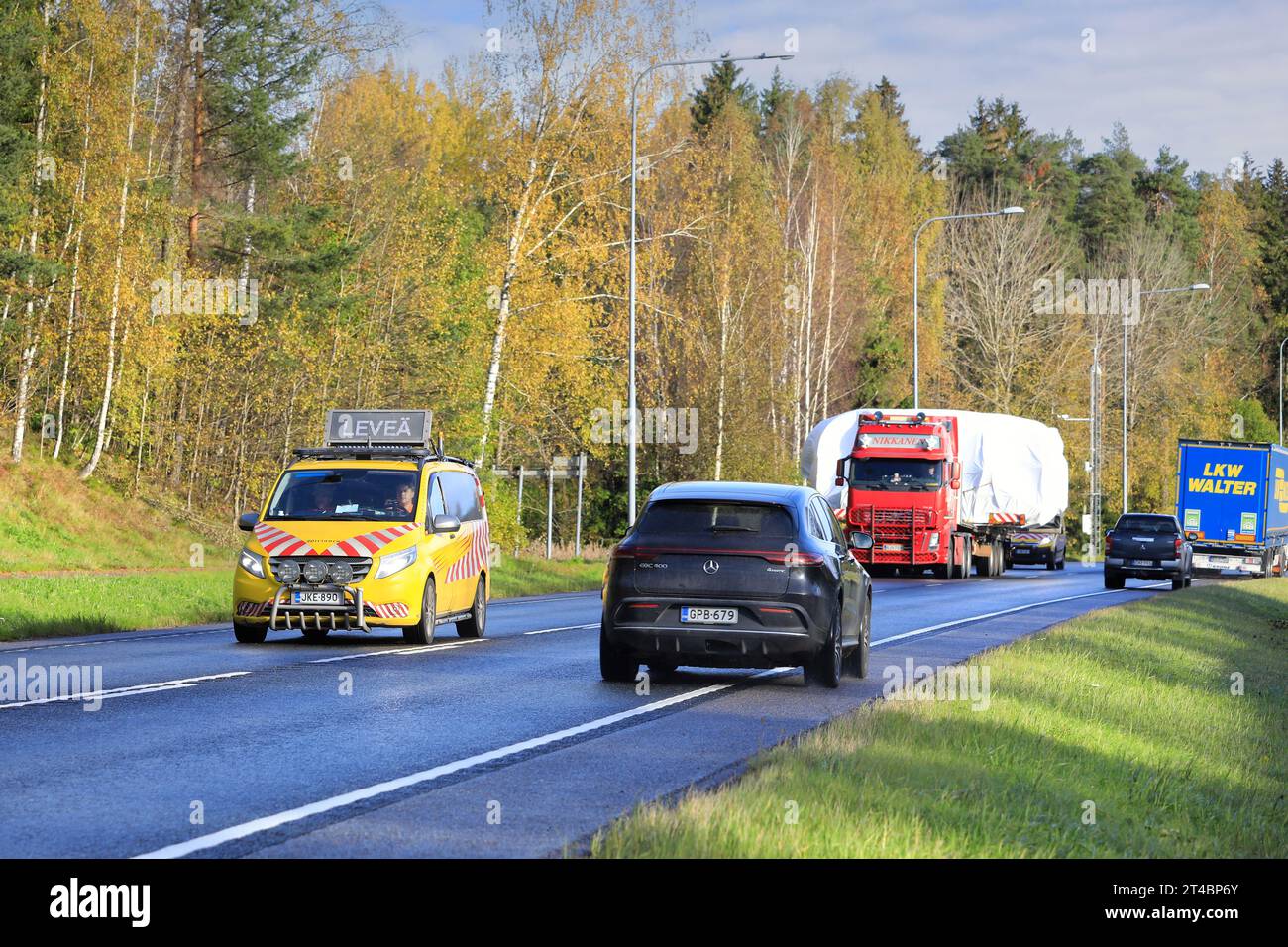 Der rote Volvo FH-Lkw-Tieflader M Nikkanen Ky transportiert breite Lasten auf der Autobahn 25. Der entgegenkommende Verkehr weicht. Raasepori, Finnland. Oktober 2023. Stockfoto