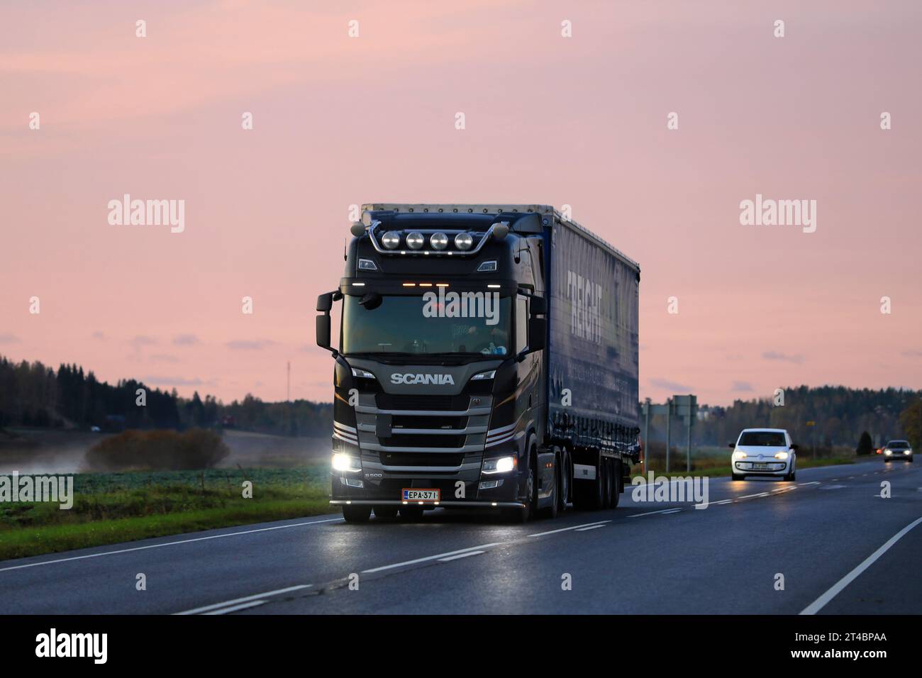 Der schwarze Scania S500-Lkw-Auflieger transportiert bei Sonnenaufgang Güter auf der Autobahn. Salo, Finnland. Oktober 2023. Stockfoto