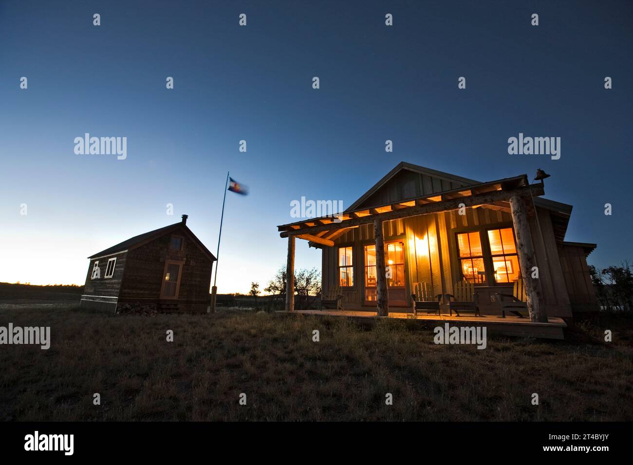 Die Außenfassade zweier Gebäude und die Flagge in der Abenddämmerung auf dem Uncompahgre-Plateau, Colorado. Stockfoto