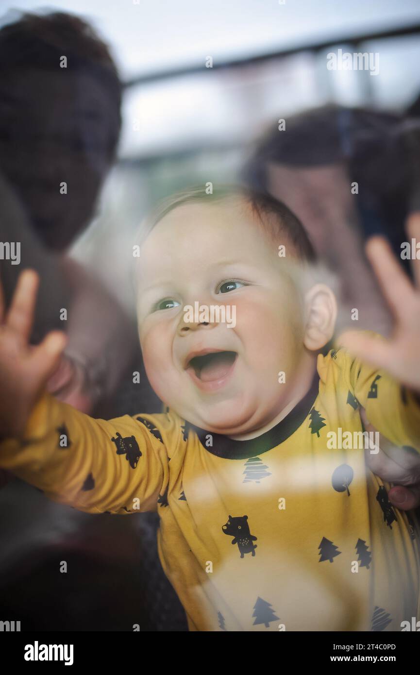 Porträt eines süßen lächelnden Jungen, der durch das Fenster schaut. Freude und Glück Konzept. Liebe und familiäre Emotionen Stockfoto