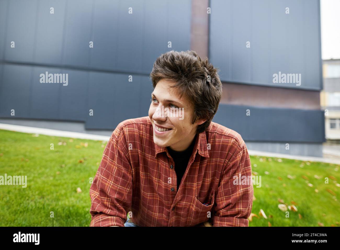 Lächelnder Student, der im Innenhof des Campus wegschaut Stockfoto