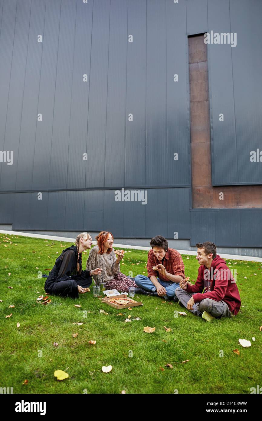 Die Studenten essen Pizza und lachen im Innenhof des Campus Stockfoto