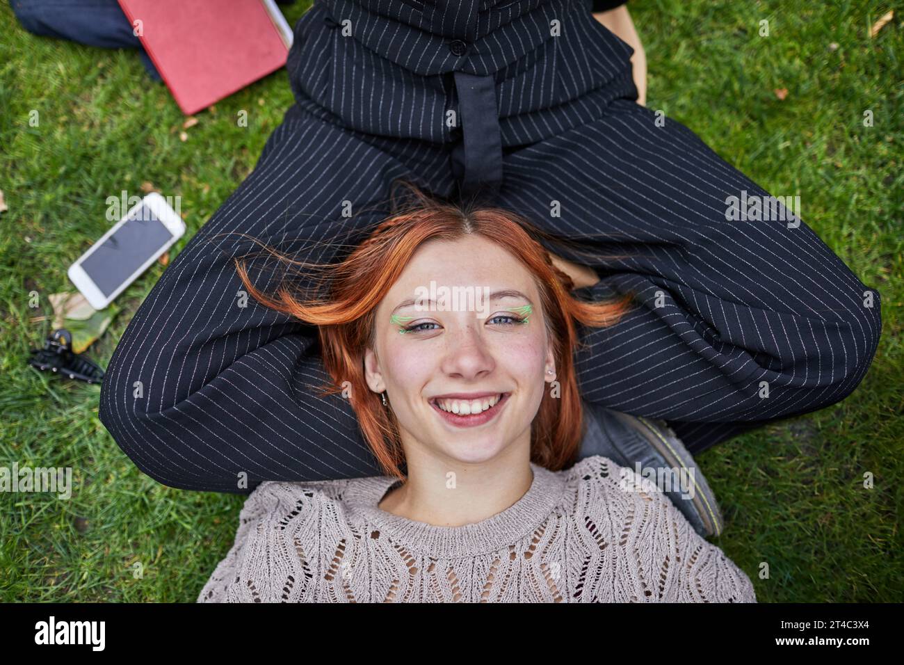 Das Teenager-Mädchen ruht auf dem Schoß ihrer Freundin auf der Wiese aus Stockfoto