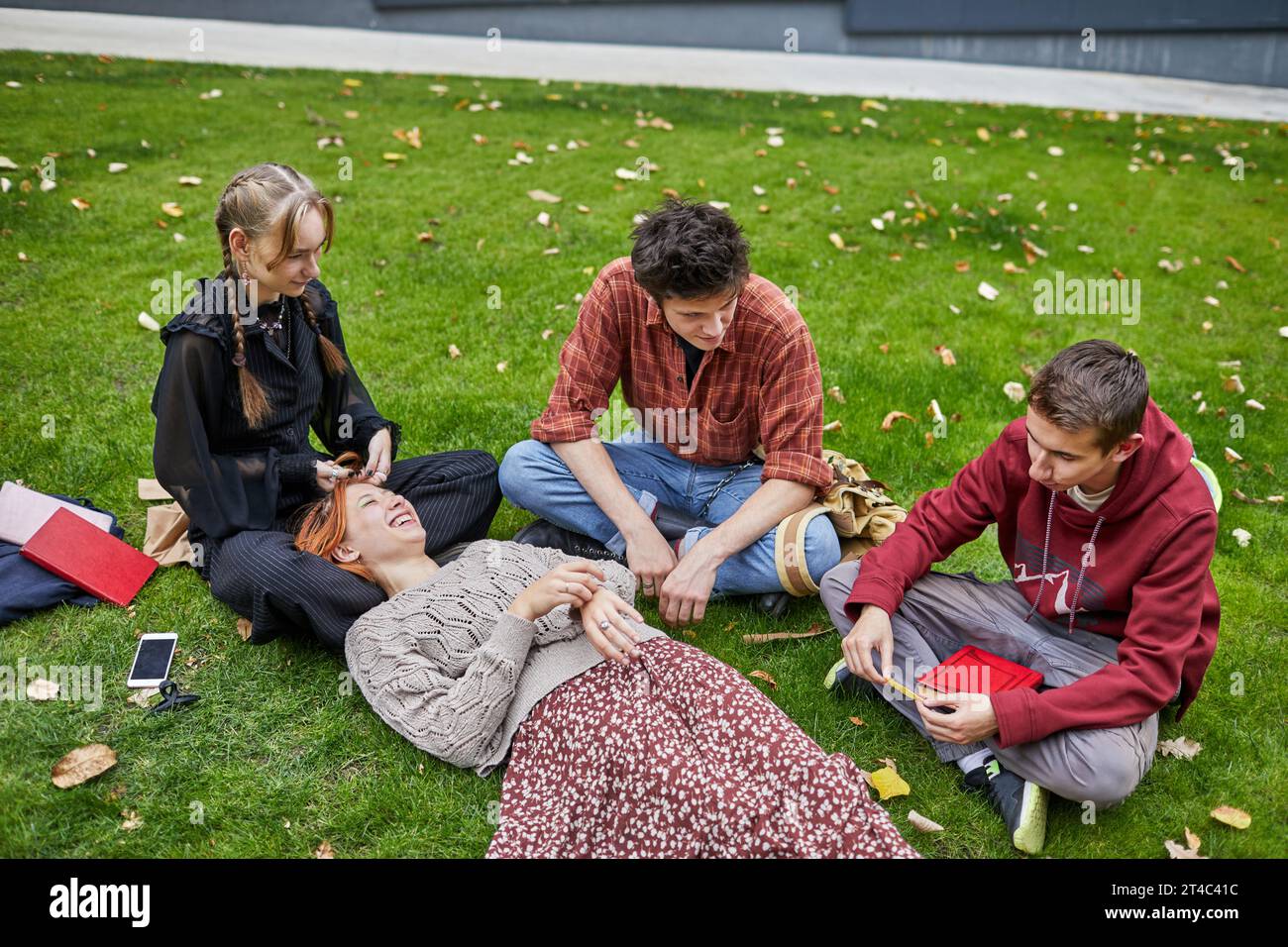 Lächelnde Schüler ruhen sich auf dem Rasen aus Stockfoto