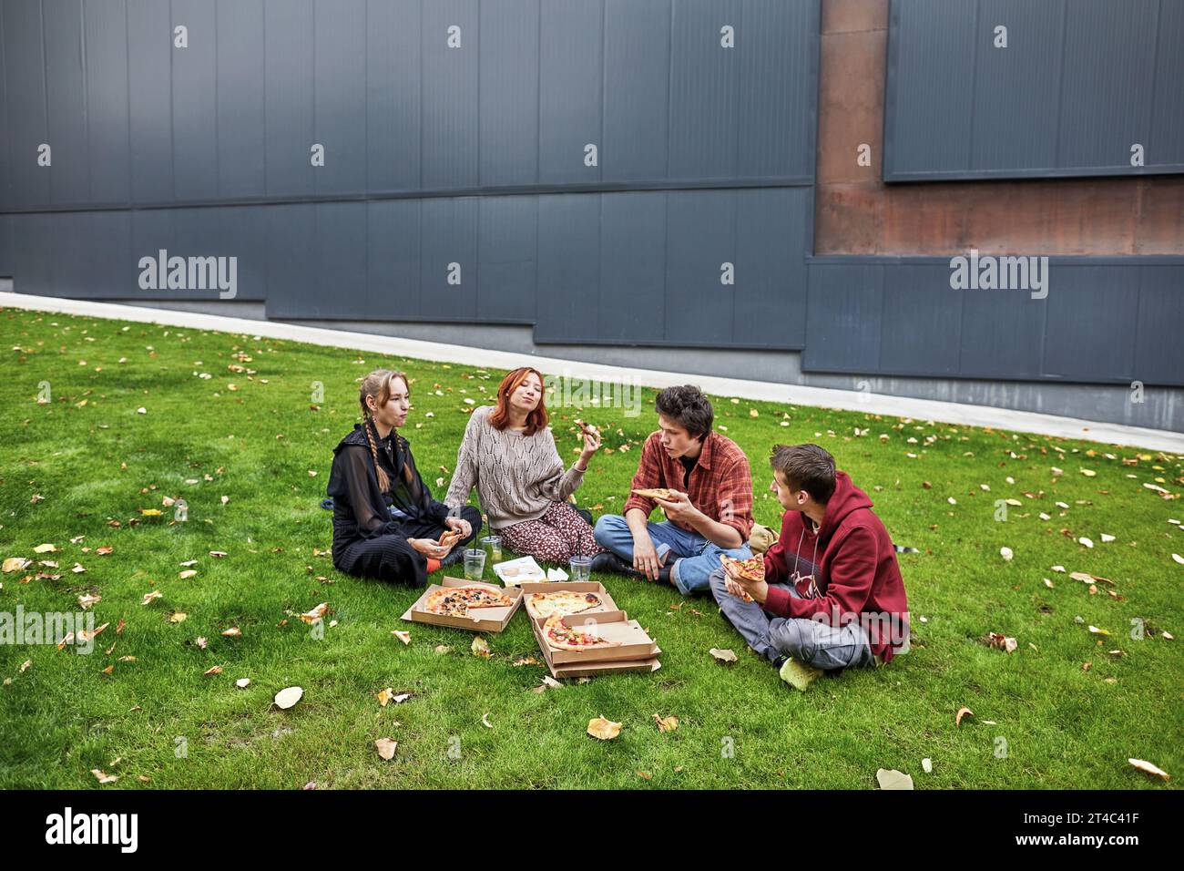 Junge Leute plaudern und essen Pizza im Innenhof des Campus Stockfoto