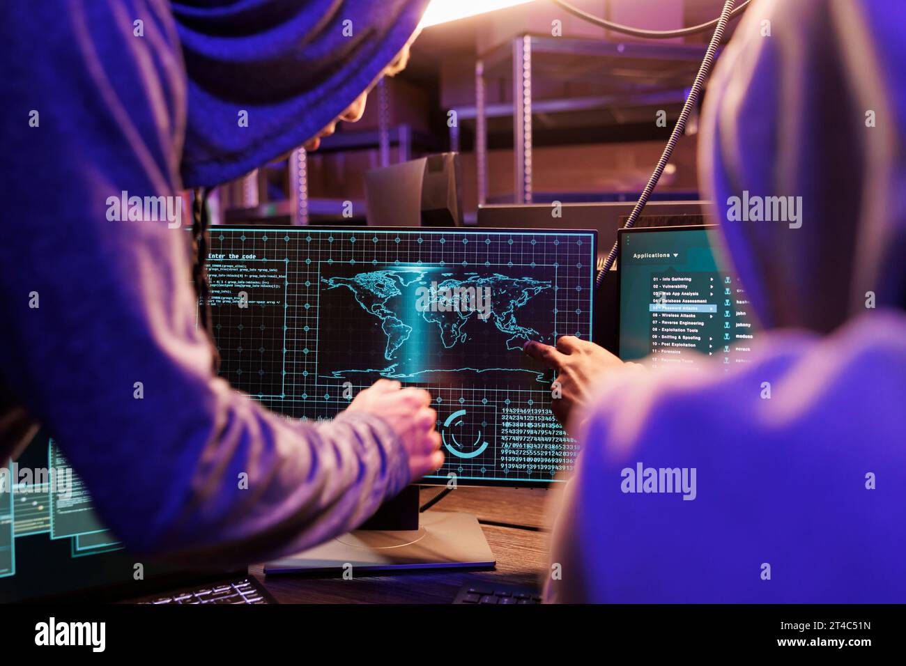 Hacker verwenden Spyware auf dem Computerbildschirm, während sie zusammenarbeiten. Zwei Kriminelle in der Kapuze knacken Passwort und überprüfen vertrauliche Informationen auf dem Internet-Server im Versteck Stockfoto
