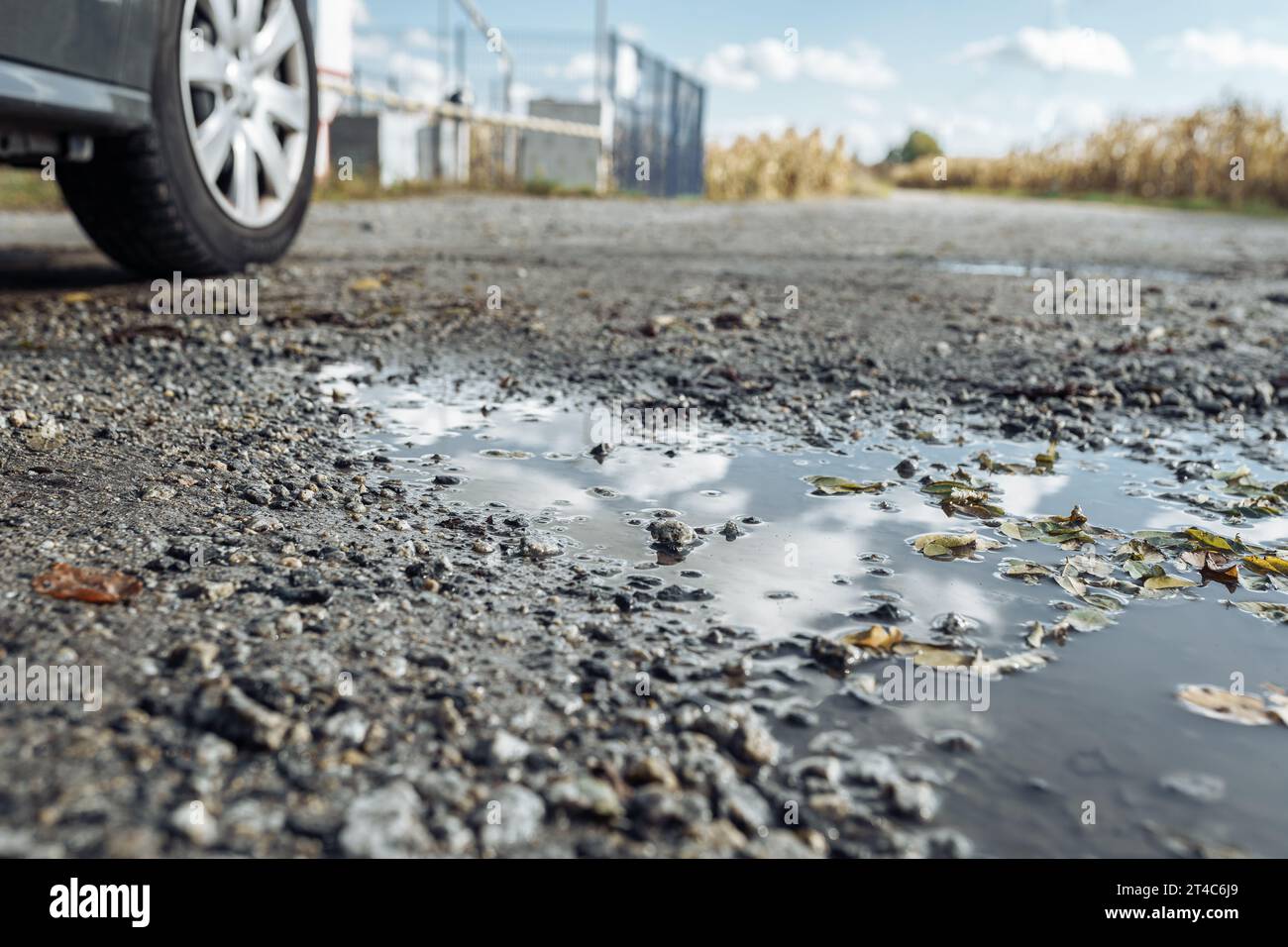 Pfützen mit Himmelsreflektion auf Schotterpiste Stockfoto