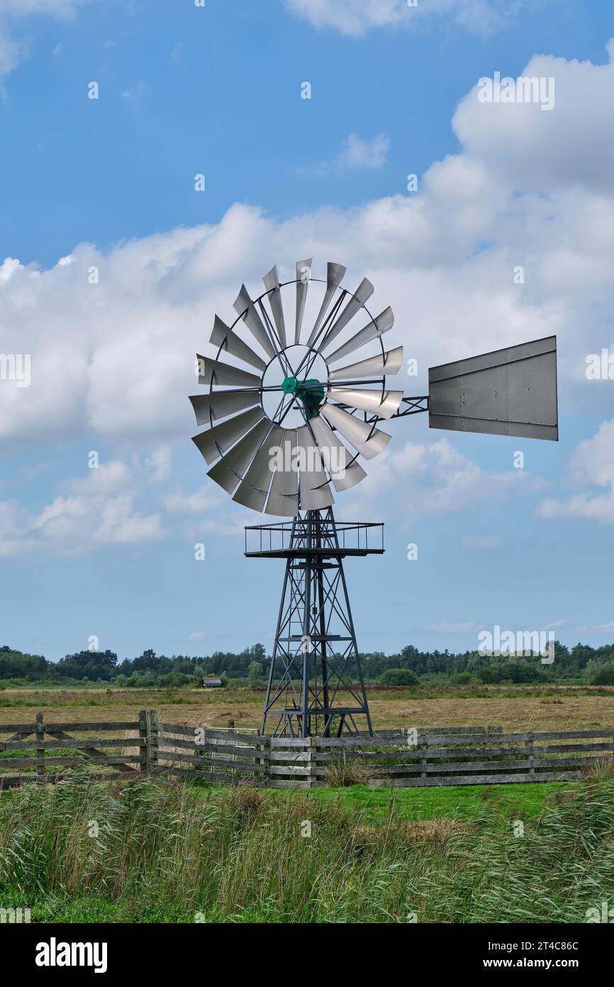 Eine amerikanische Windmaschine vor blauem Himmel mit Wolken in einer ländlichen Gegend. Stockfoto