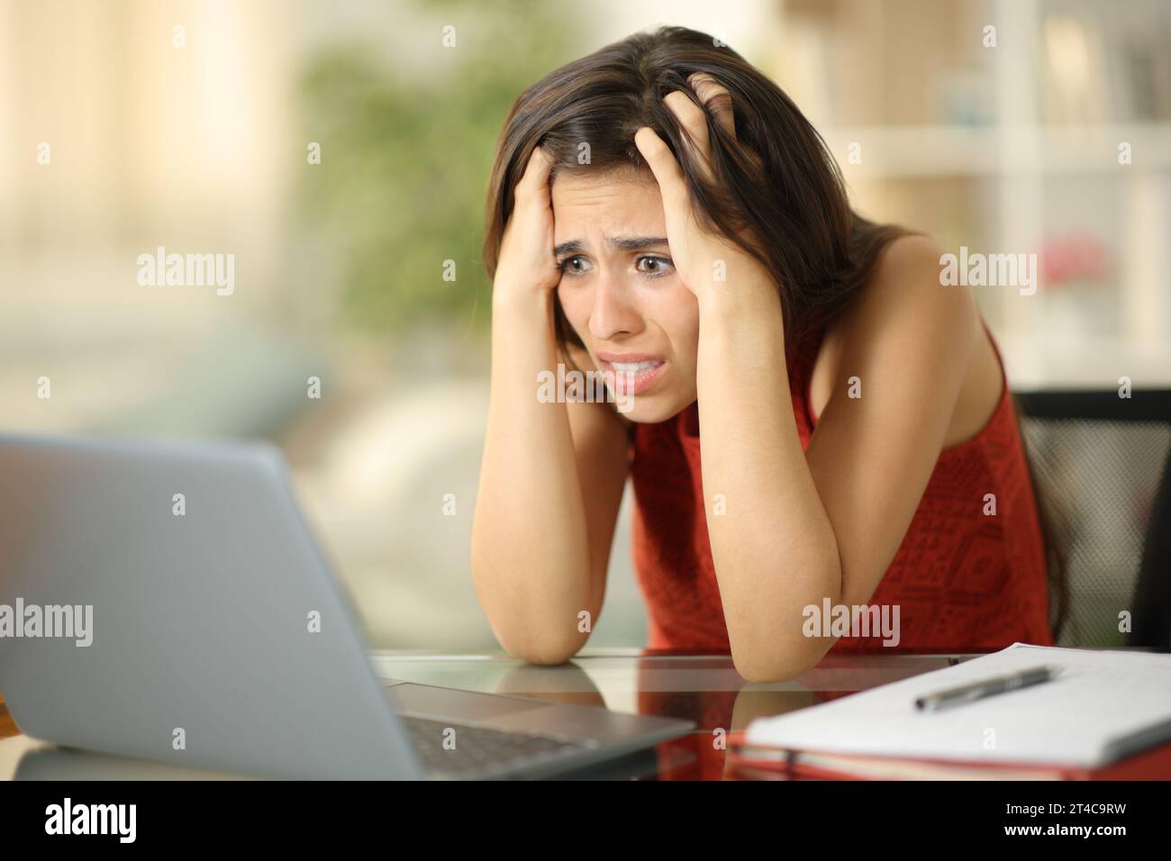 Verängstigter Student, der zu Hause schlechte Nachrichten auf dem Laptop liest Stockfoto