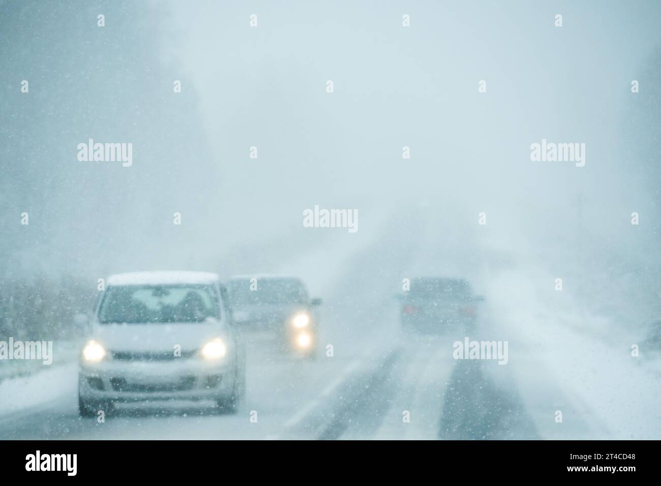 Das Auto fährt auf einer Winterstraße in einem Schneesturm. Stockfoto