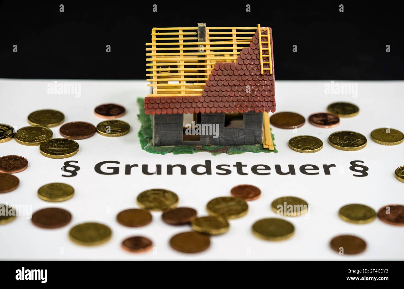 Wortgrundsteuer mit Euro-Münzen und Haus im Bau Stockfoto