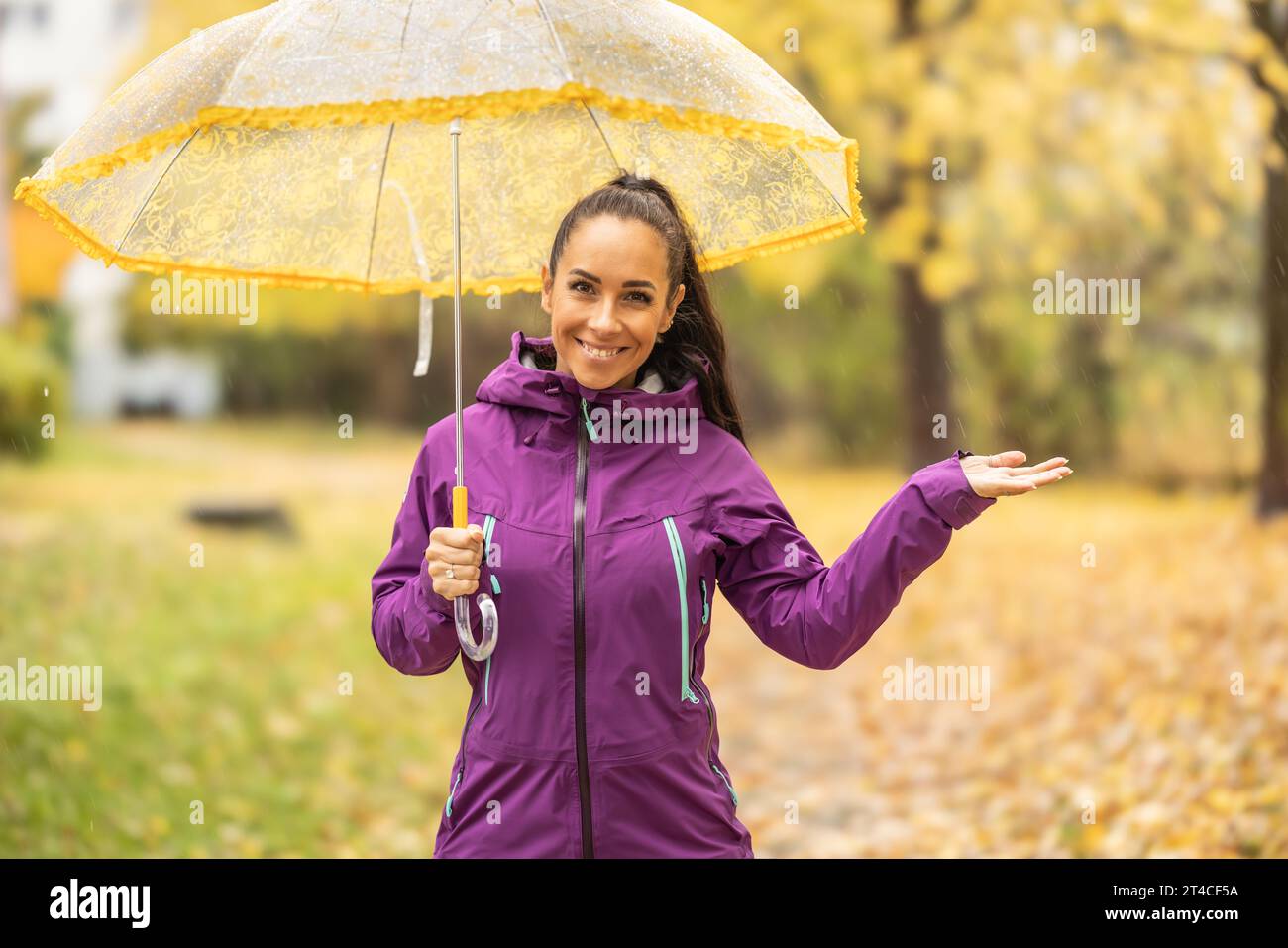 Porträt einer jungen lächelnden Frau unter einem Schirm auf einem Spaziergang im Herbstpark. Stockfoto