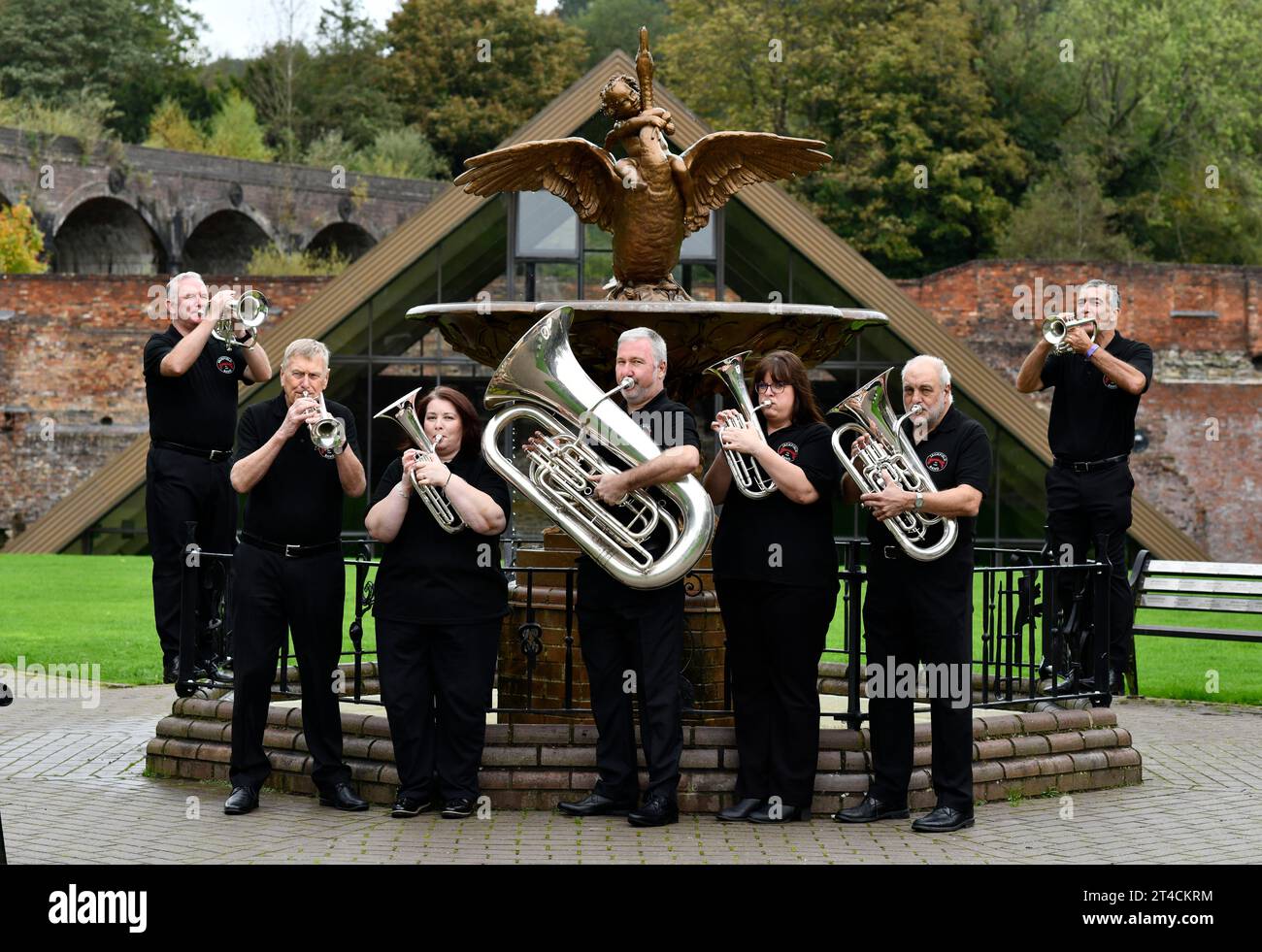 Mitglieder der Jackfield Band und der Boy and Swan gusseiserne Wasserbrunnen im Coalbrookdale Museum of Iron. Hier findet das Brass Band Festival statt Stockfoto