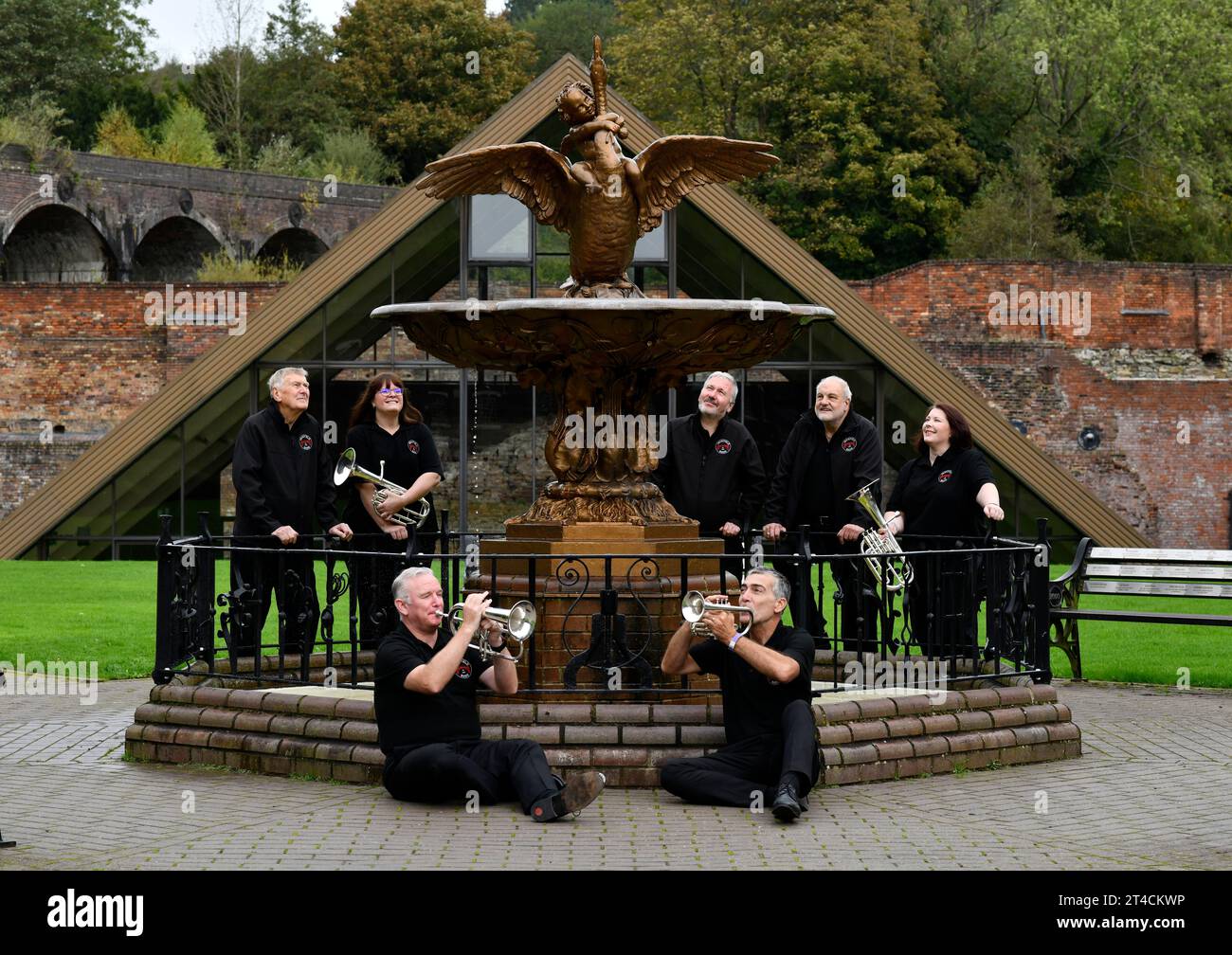 Mitglieder der Jackfield Band und der Boy and Swan gusseiserne Wasserbrunnen im Coalbrookdale Museum of Iron. Hier findet das Brass Band Festival statt Stockfoto