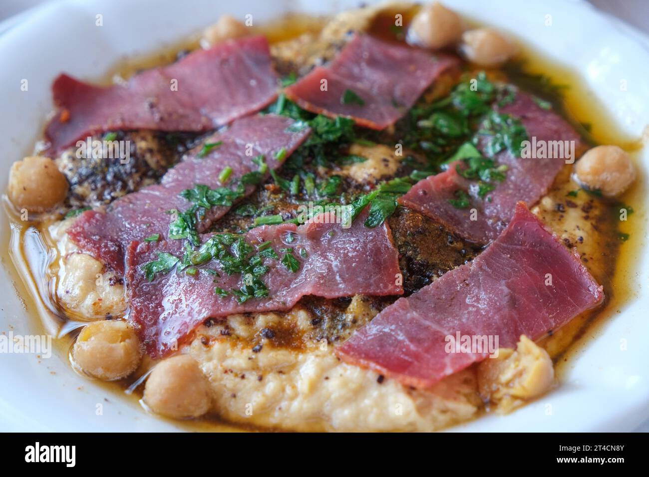 Schließen Sie Hummus mit Pastrami in der Schüssel. Libanesische Kichererbsen-Dipping-Sauce-Vorspeise. Stockfoto