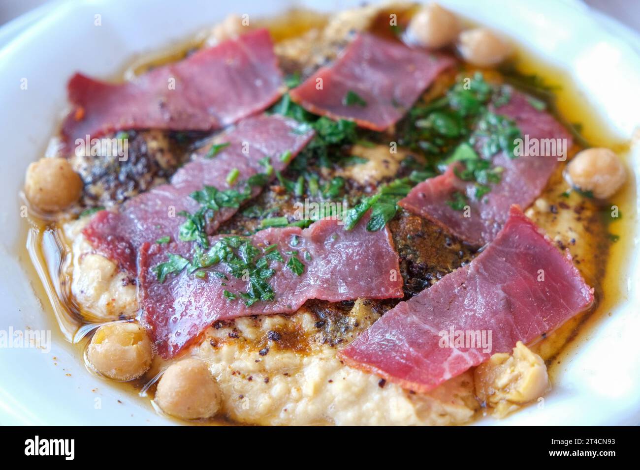 Schließen Sie Hummus mit Pastrami in der Schüssel. Libanesische Kichererbsen-Dipping-Sauce-Vorspeise. Stockfoto