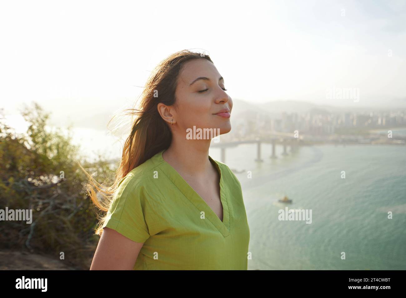 Schöne junge Frau mit geschlossenen Augen, die mit Wind auf ihrem Gesicht atmet und die Sonne bei Sonnenuntergang genießt. Schönheit Sonnenschein Mädchen Seitenprofil Porträt. Po Stockfoto