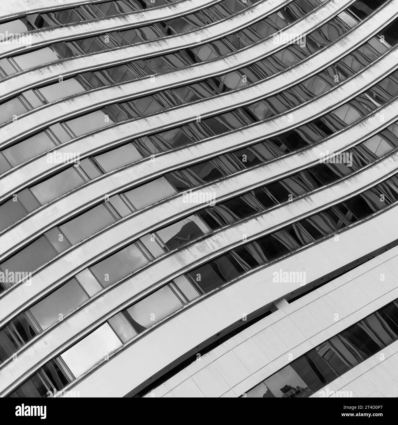 Dieses Graustufenbild erfasst die geschwungenen Formen eines modernen architektonischen Gebäudes. Die fließenden, welligen Linien der Fassade betonen ein Gefühl von Mo Stockfoto