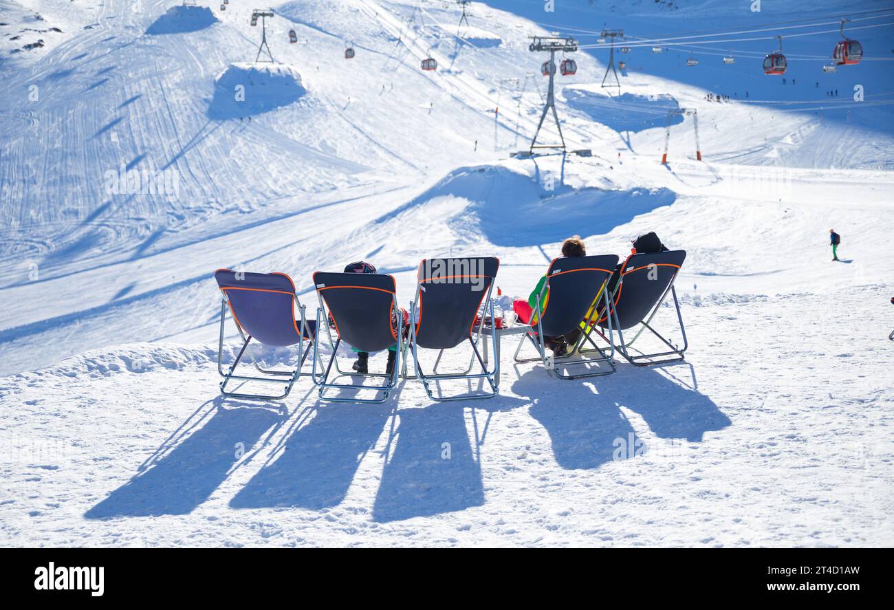 Touristen, die auf dem Liegestuhl sitzen, genießen Sonnenschein auf dem Stubaier Gletscher Stockfoto