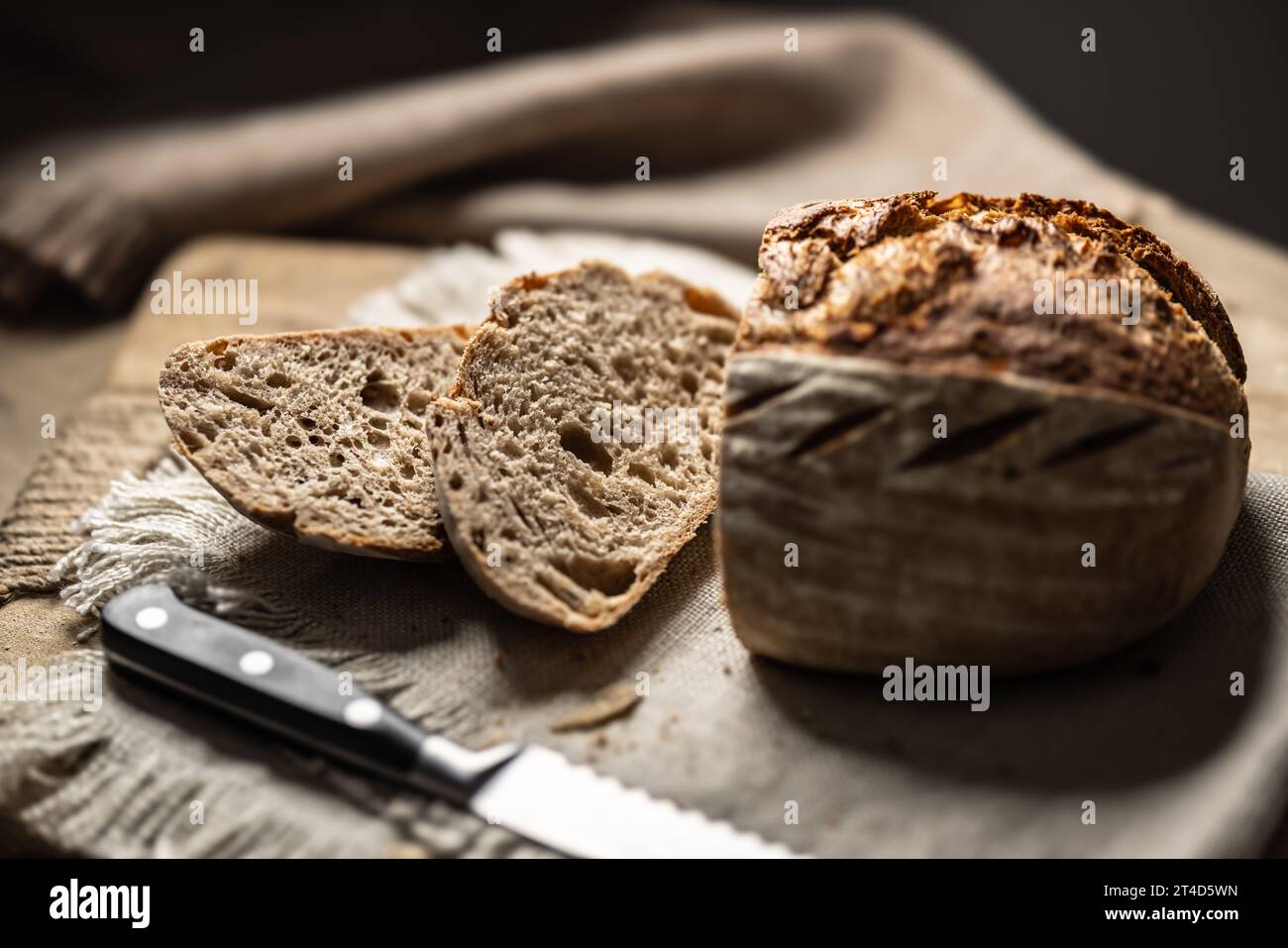 Frisches Sauerteigbrot mit einer geschnittenen Scheibe auf einem Schneidebrett. Stockfoto