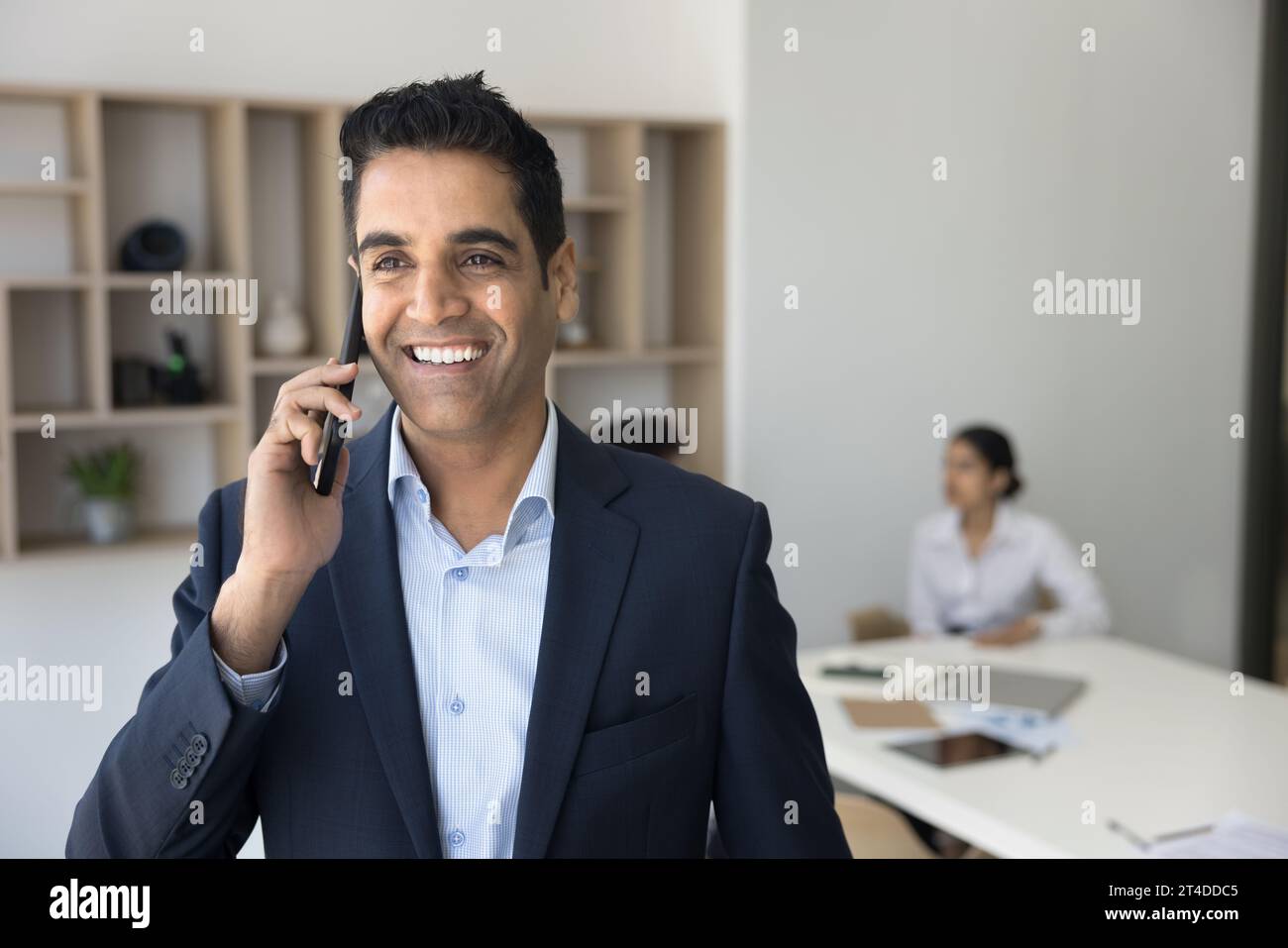 Fröhlicher, erfolgreicher, gutaussehender Geschäftsmann, der Mobiltelefonanrufe genießt Stockfoto