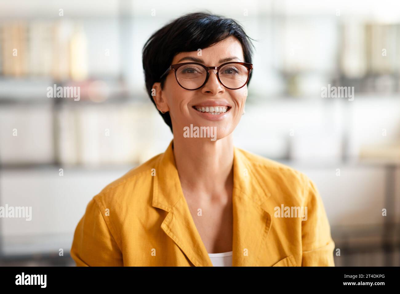 Eine europäische Geschäftsfrau mittleren Alters lächelte in die Kamera und trug eine Brille drinnen Stockfoto