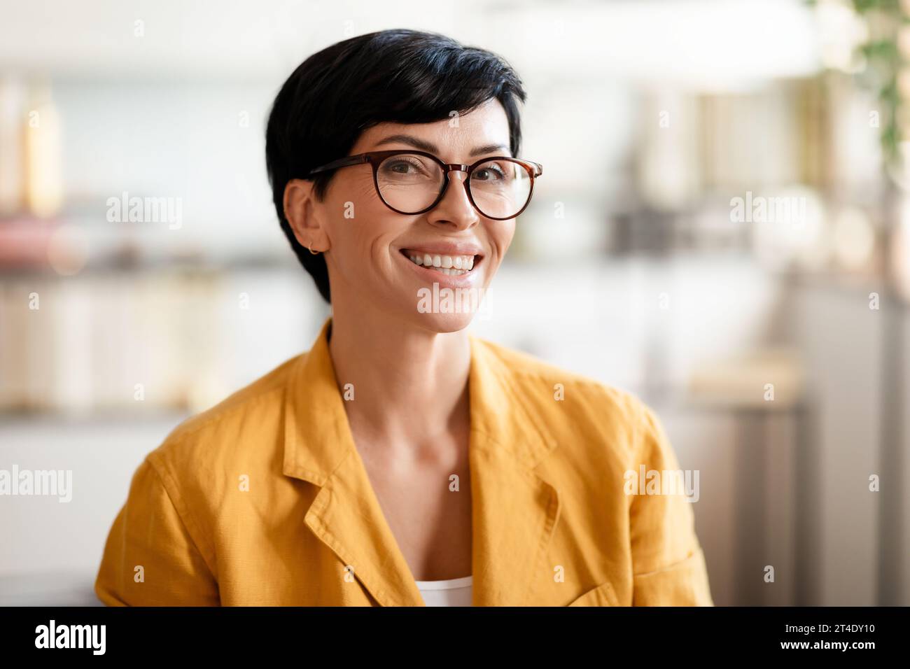 Porträt einer glücklichen Frau mittleren Alters, die drinnen in die Kamera lächelt Stockfoto