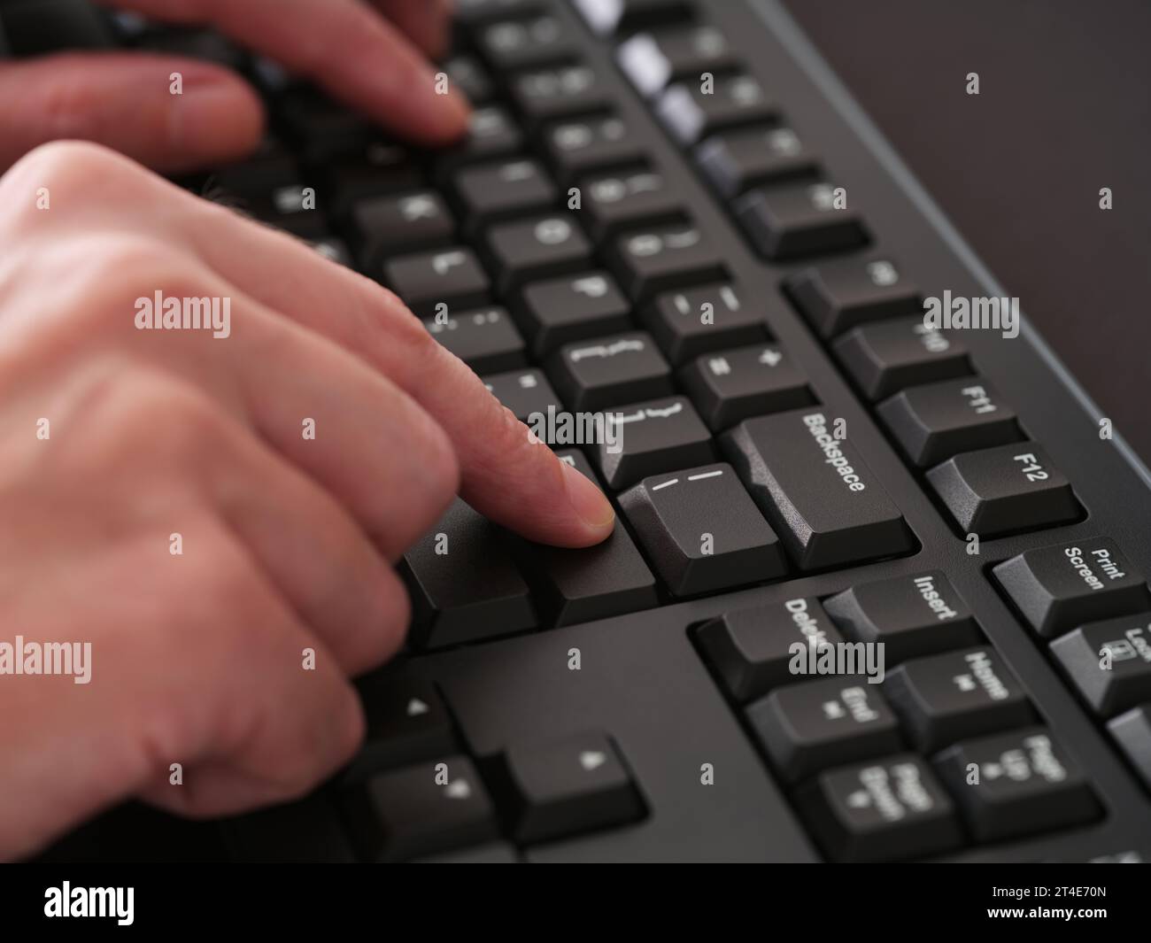 Ein Mann, der auf einer schwarzen Computertastatur tippt. Nahaufnahme. Stockfoto