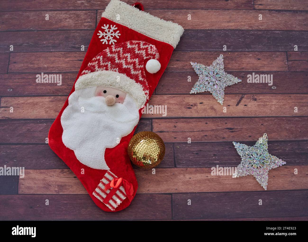 Weihnachtsdekoration. Weihnachtsmannstrumpf mit leuchtenden Sternen und einer goldenen Kugel. Hölzerner Hintergrund. Horizontal Stockfoto