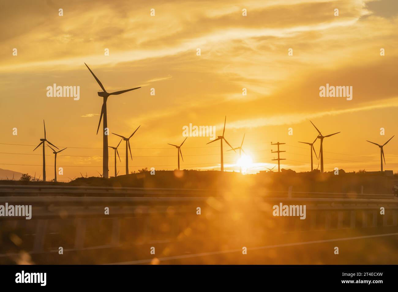 Windkraftanlage bei Sonnenuntergang von einem Autofenster. Erneuerbare Energien gegen die globale Erwärmung Stockfoto