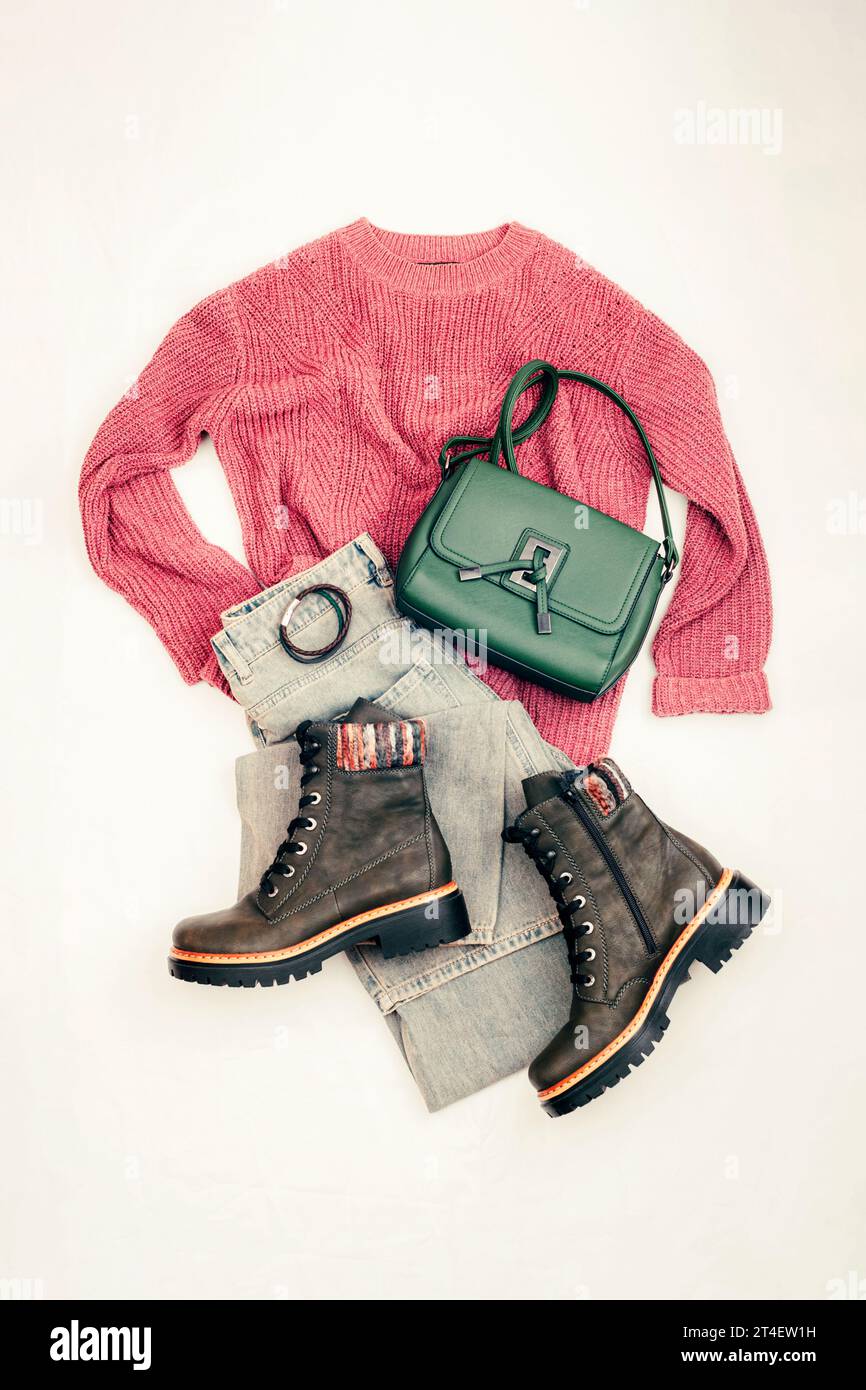 Violetter Pullover, breite Vintage-Jeans, grüne Tasche und Stiefel. Bequeme Freizeitbekleidung für Damen auf hellem Hintergrund. Draufsicht, flach. Stockfoto