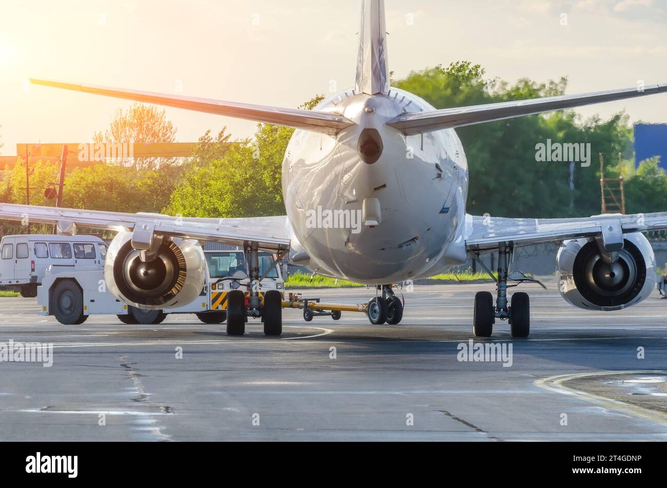Das Flugzeug führt die Push-Back-Operation am Flughafen aus. Flugzeugservice für Flüge vor dem Abflug am Abend bei Sonnenaufgang. Stockfoto