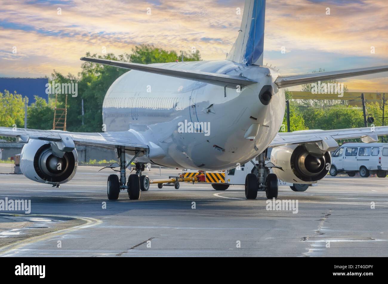 Das Flugzeug führt die Push-Back-Operation am Flughafen aus. Flugzeugservice für Flüge vor dem Abflug am Abend bei Sonnenuntergang. Stockfoto