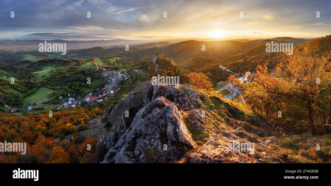 Berge bei Sonnenuntergang in der Slowakei - Vrsatec. Landschaft mit Berghügeln, Orangenbäumen und Gras im Herbst, farbenfroher Himmel mit goldenen Sonnenstrahlen. Panorama Stockfoto